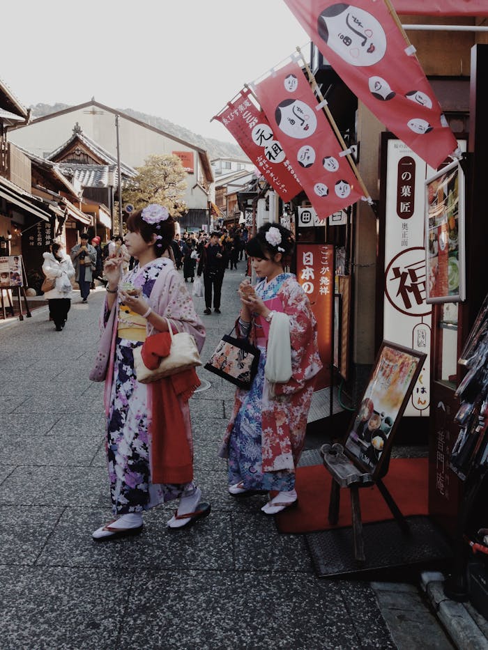 Two women in colorful kimonos stroll through a traditional street in Kyoto, showcasing Japanese culture.